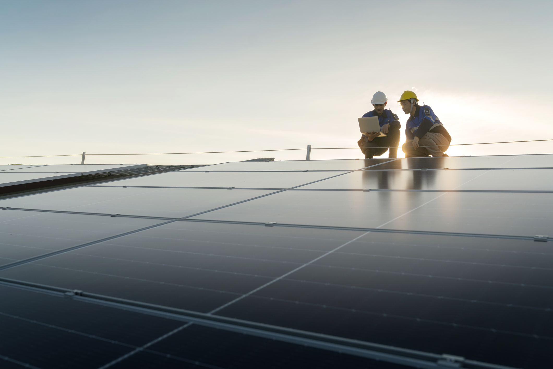 Specialist technician professional engineer with laptop and tablet maintenance checking installing solar roof panel on the factory rooftop under sunlight Engineers team survey check solar panel roof