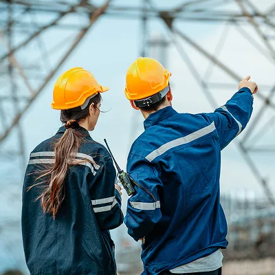 Due diligence ambientale Protos crop 400x400 | Protos Group Two construction workers wearing yellow hard hats review a steel framework on a construction site. | Protos Group